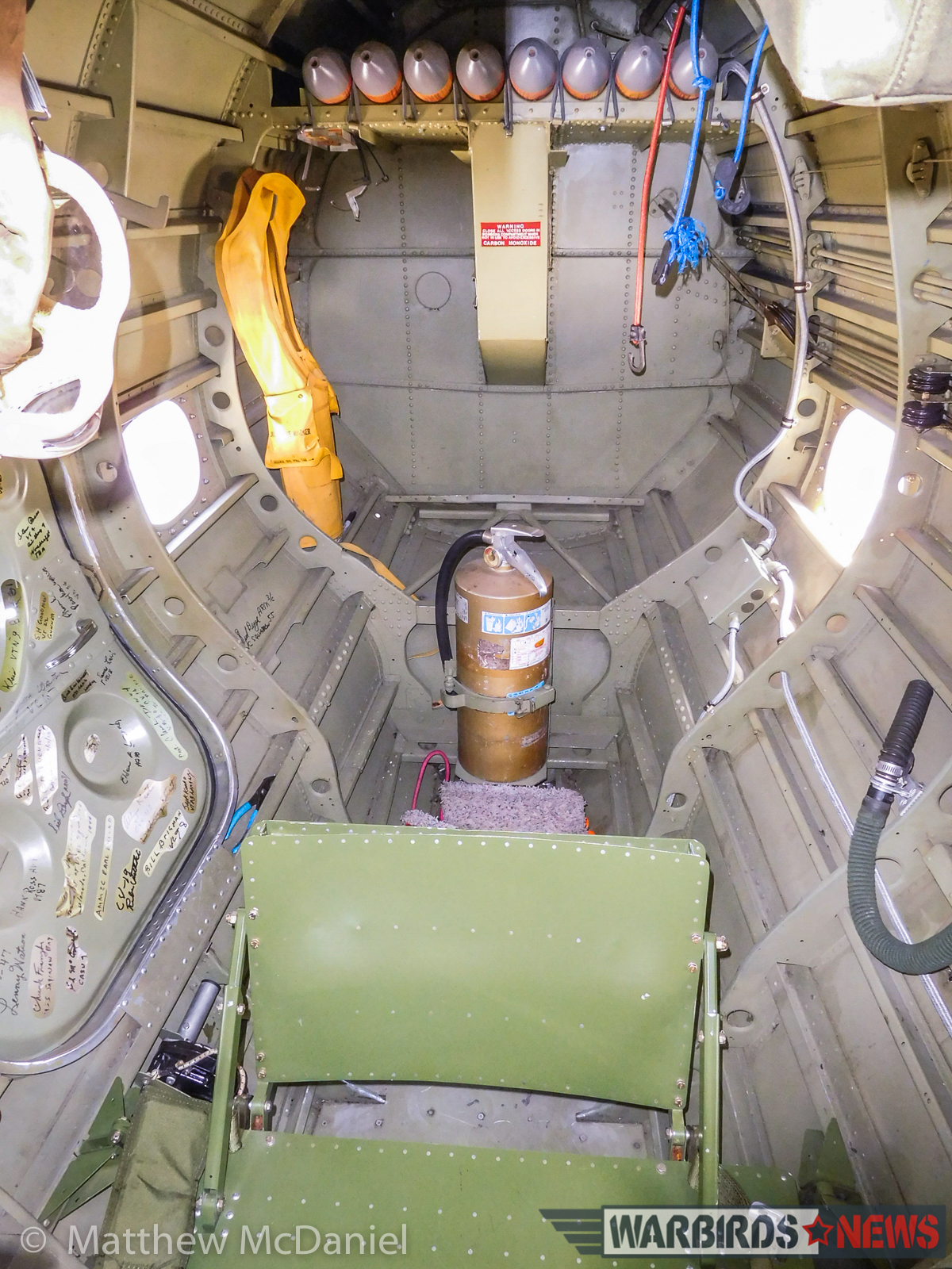 The bombardier/radioman position in the lower tail of Deckert's TBM (looking aft). Earlier versions of the TBM included a ventral machine gun and additional window when the fire-extinguisher sits in this later -3 model. Note the signatures on the compartment's entry hatch; They are those of WWII-vet TBM crew members who've been reunited with the TBM by Deckert and his team. (Photo by Matthew McDaniel)