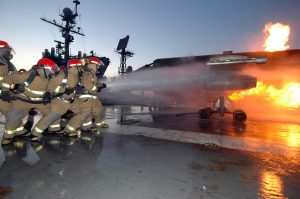 A repair locker hose team aboard USS John F. Kennedy (CV 67) combats a controlled fire on the MAFTD.  (Image Credit: US Navy)