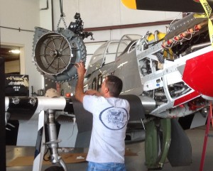 Mustang expert, from Vintage V12s in California guides the heavyweight supercharger back to its place. (Image Credit: CAF Dixie Wing)