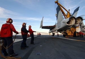 Crash and salvage personnel keep an F/A-18 Hornet training airframe steady as it is lifted from the landing area during a simulated crash landing aboard the USS Harry S. Truman (CVN 75) (Image Credit: US Navy)