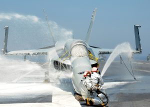 Sailors assigned to the crash and salvage crew on  USS George H.W. Bush (CVN 77) spray foam on an F/A-18 Hornet training aircraft during a firefighting drill. (Image Credit: US Navy)