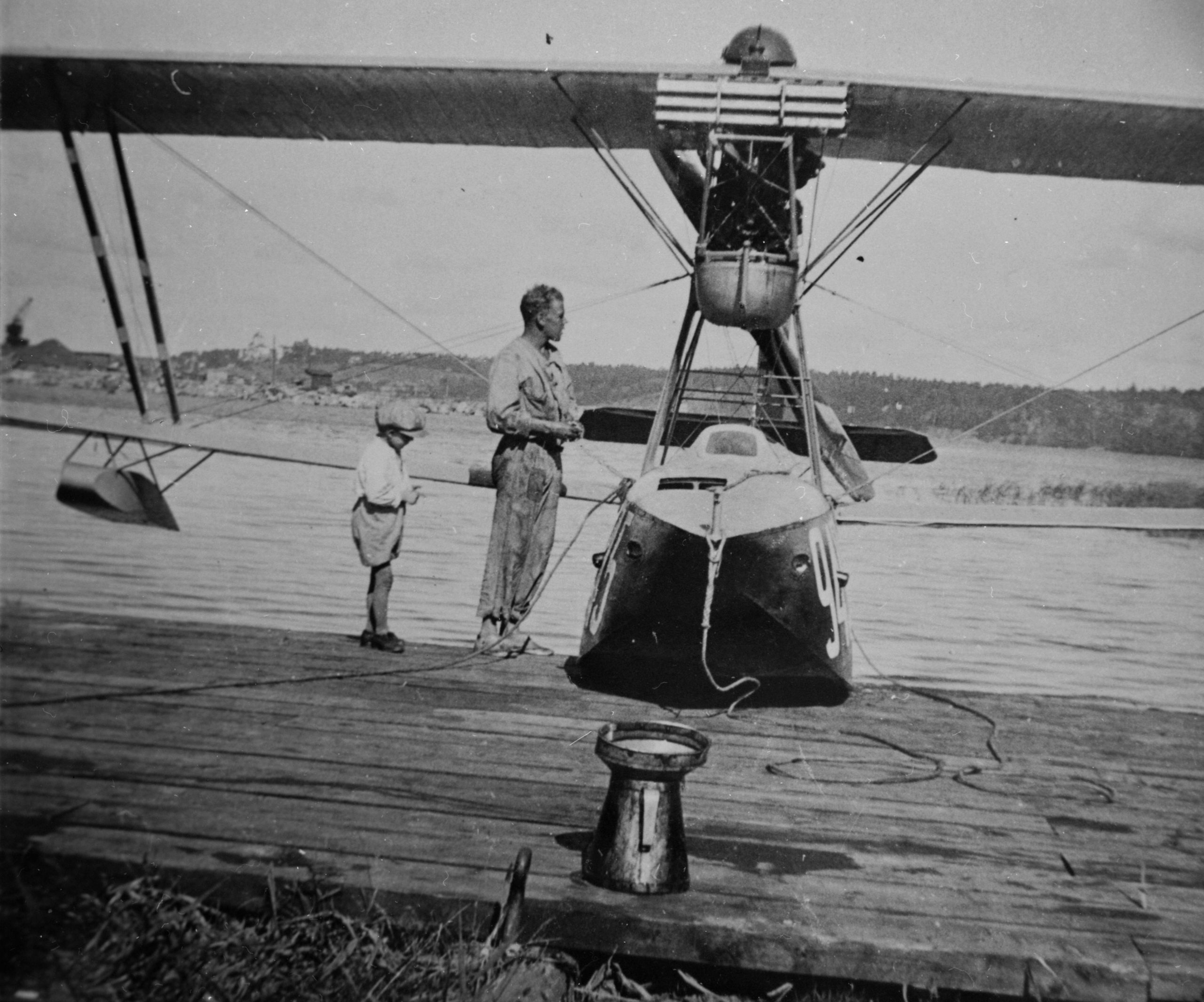 A man and a boy are standing by airplane Macchi M.7 at Lake Roxen at the Berg locks scaled
