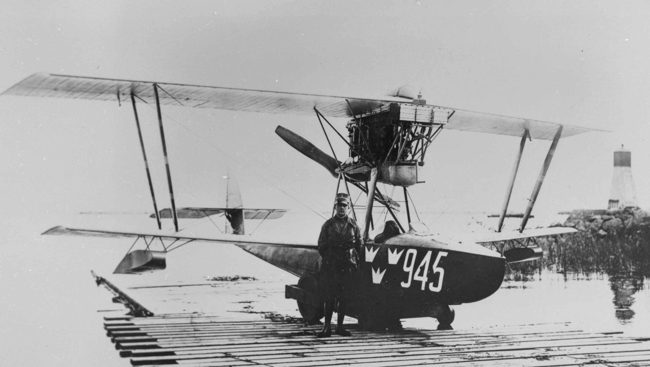 A military man stands by airplane Macchi M.7 marked number 945 at a jetty at Lake Roxen at Bergs locks. The man is Nils Kindberg scaled