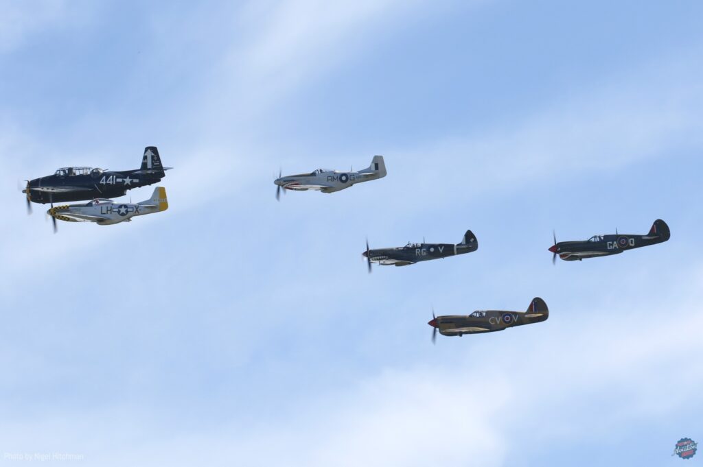 A “Balbo” flypast of some of the attending WWII aircraft was led by Paul Bennet Airshows' TBM, flanked by the Mustangs of Doug Hamilton (left) and 100 Sqn RAAF, followed by that unit's Spitfire Mk.VIII and finally the Kittyhawks of Ross Pay (lower) and Allan Arthur. [Photo by Nigel Hitchman]