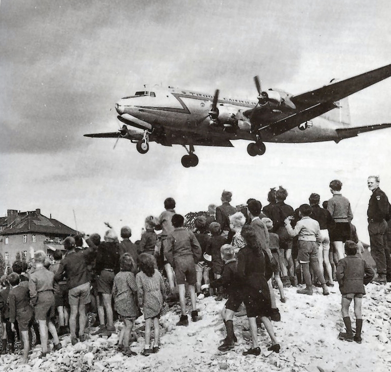 Berliners watch a C-54 Skymaster land at Tempelhof Airport, 1948 .USAF - United States Air Force Historical Research Agency via Cees Steijger ( Wikipedia)