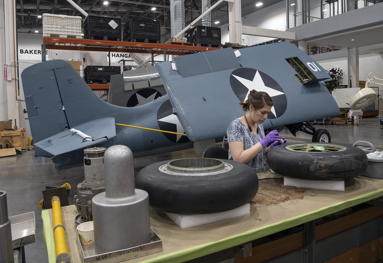 Conservator Maggie Bearden treats the tires for the Eastern Division FM 1 Wildcat in the Mary Baker Engen Restoration Hangar Smithsonian photo by Mark Avino