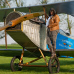 Gigi Coleman standing on the wheel of a Curtiss JN-4 "Jenny", built by Chapter 1414 of the Experimental Aircraft Association and the Vintage Wings and Wheels Museum, at Poplar Grove, Illinois in 2014. [Photo by Leonardo Correa Luna]