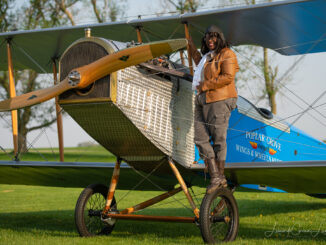 Gigi Coleman standing on the wheel of a Curtiss JN-4 "Jenny", built by Chapter 1414 of the Experimental Aircraft Association and the Vintage Wings and Wheels Museum, at Poplar Grove, Illinois in 2014. [Photo by Leonardo Correa Luna]