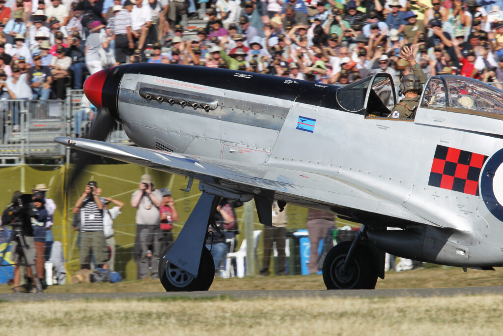 Graham Bethell waves to the Wanaka crowd from his P-51D Mustang ZK-TAF. [Photo via Warbirds Over Wanaka]