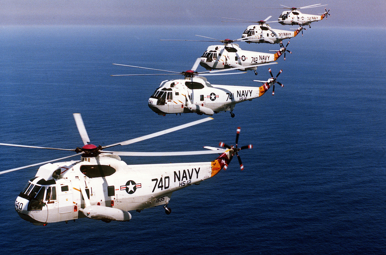 Five U.S. Navy Sikorsky SH-3H Sea King anti-submarine warfare helicopters from Helicopter Anti-Submarine Squadron HS-12 "Wyverns" flying in formation, in 1985. HS-12 was assigned to Carrier Air Wing 5 (CVW-5) aboard the aircraft carrier USS Midway (CV-41). ( Image credit US NAVY via Wikipedia)