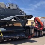 Strapped to a flatbed trailer towed by Polar King International TBM Avenger 91188 arrives at the Castle Air Museum restoration hangar Castle Air Museum