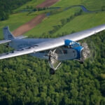 Tri Motor over woods by Jim Koepnick