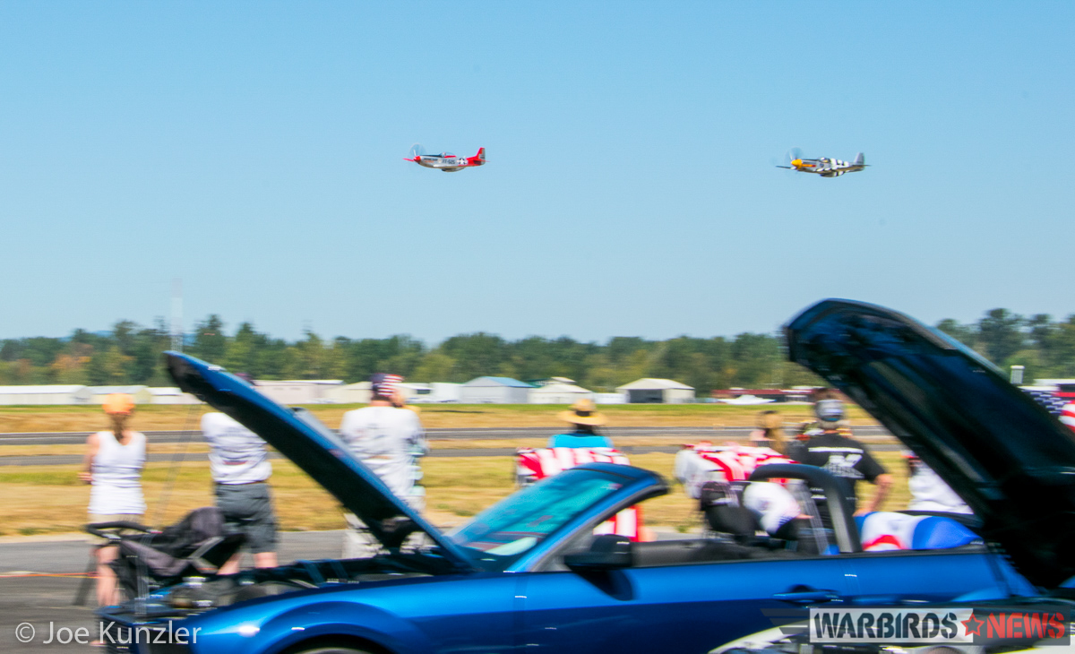 The P-51s roaring past the assembled Ford Mustangs on the tarmac. (photo by Joe Kunzler)
