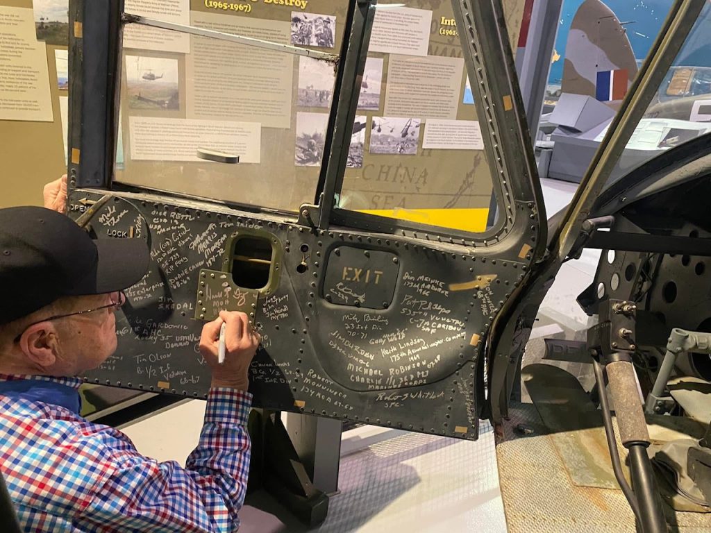 Chris Henry on Storytelling, Preservation, and the Future of the EAA Aviation Museum 17 Vietnam Veterans from the 121st AHC sign the door of our Huey The Good Widow Mrs. Jones