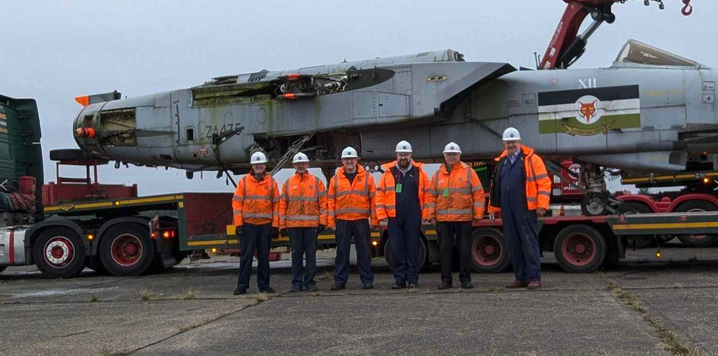 Volunteers stand in front of the Tornado ZA475 fuselage which is sitting on a trailer